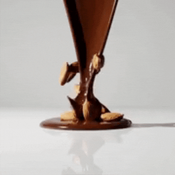 Chocolate oscuro cayendo sobre almendras naturales en cámara lenta, producto gourmet mysuplify.