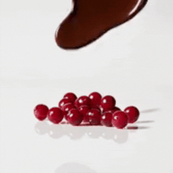 Chocolate vertiéndose sobre arándanos rojos deshidratados, mostrando un momento clave del proceso de recubrimiento en Mysuplify.